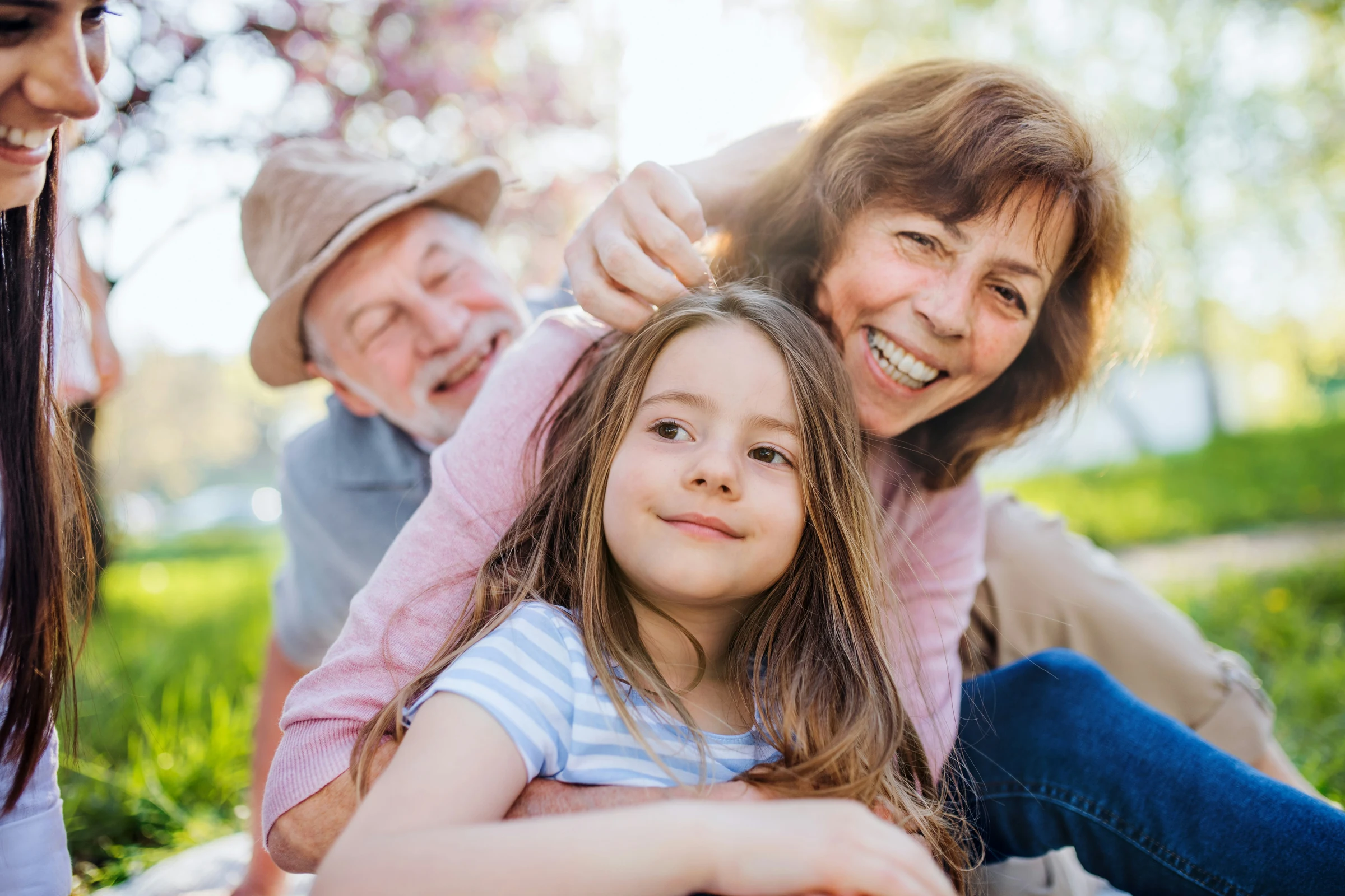 Grandparents sharing a happy moment with their granddaughter outdoors.