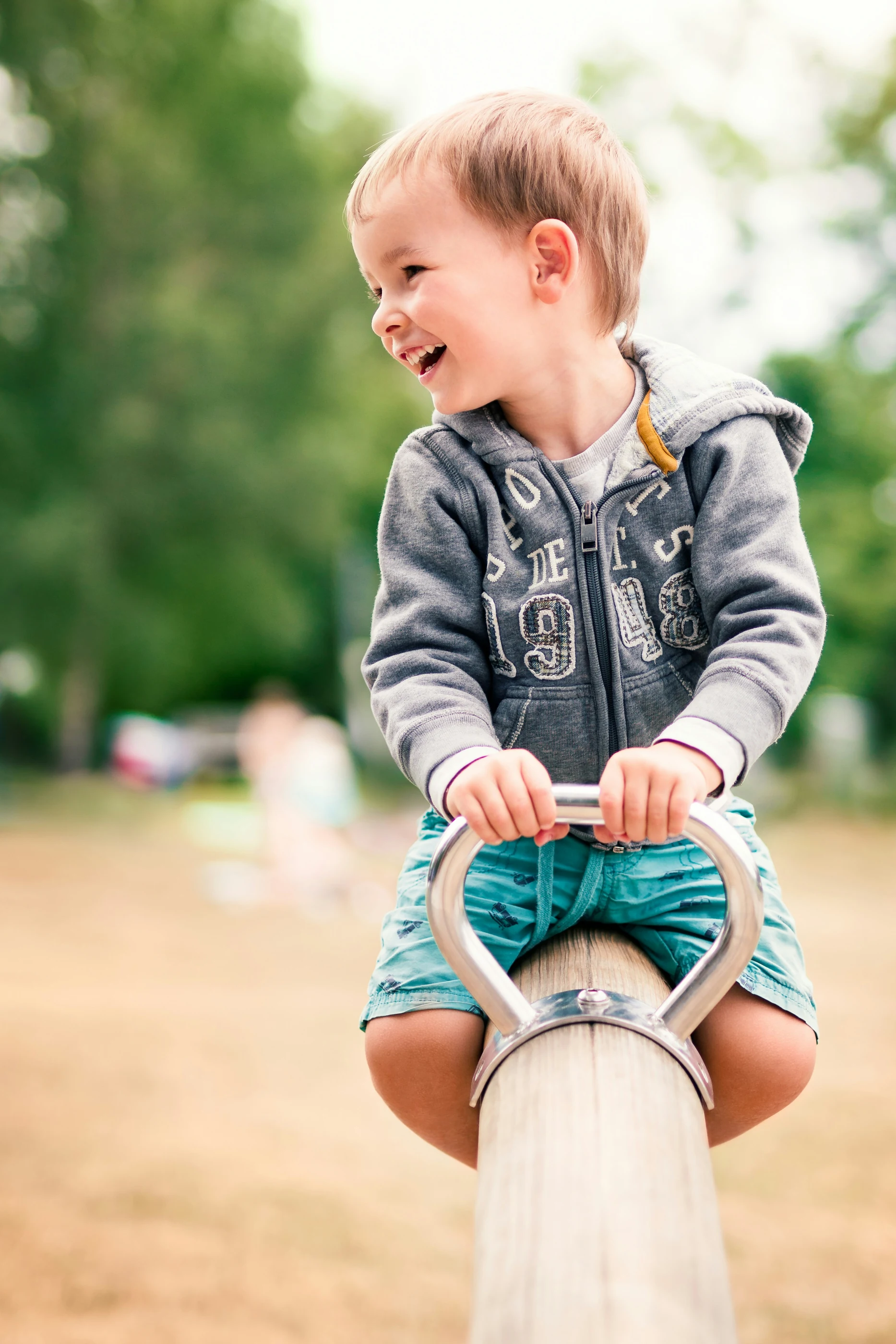 A child laughing on a playground seesaw.